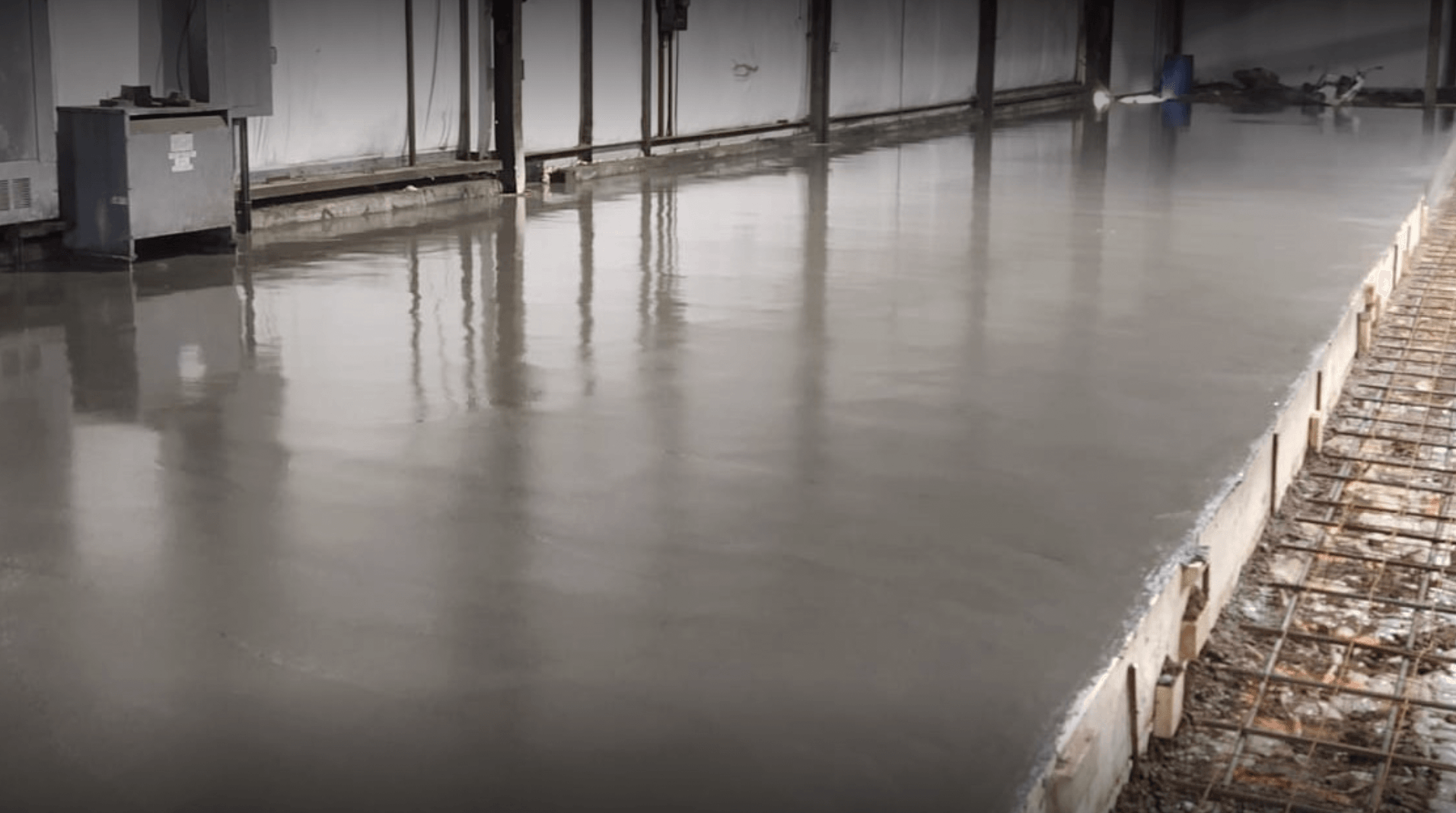 A wet concrete floor with reflections inside an industrial building