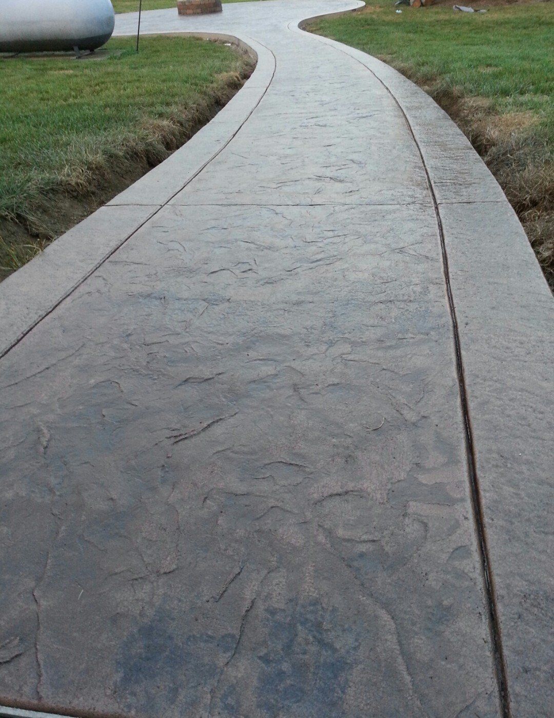 Curved concrete sidewalk bordered by grass on both sides.