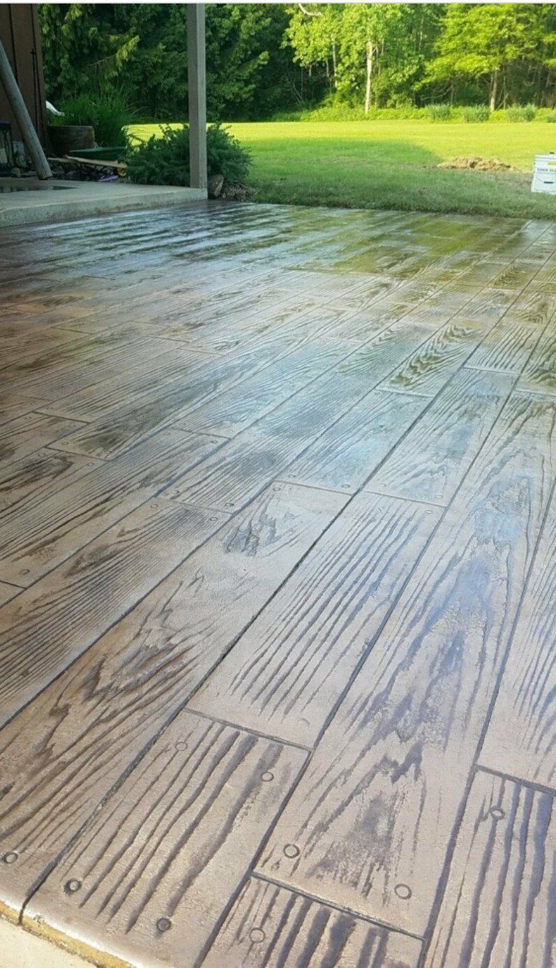 Wooden deck leading to a green lawn and trees on a sunny day
